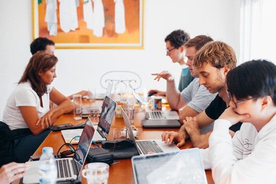 Personen sitzen vor Laptops und arbeiten