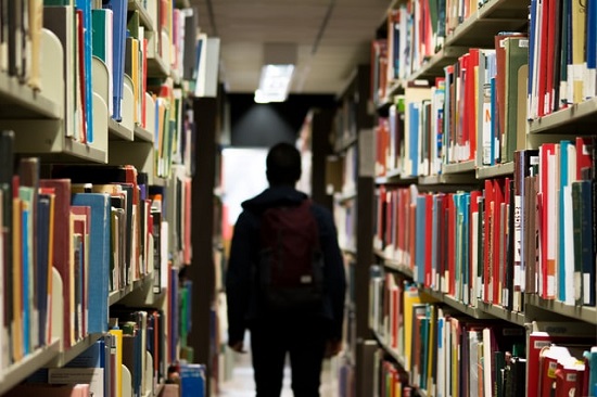 Person steht in Bibliothek Person steht in Bibliothek