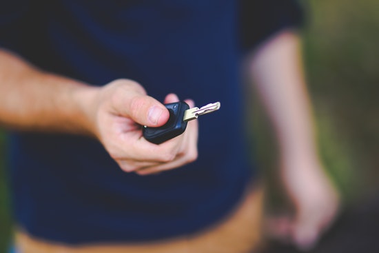 Person hält Autoschlüssel Person hält Autoschlüssel