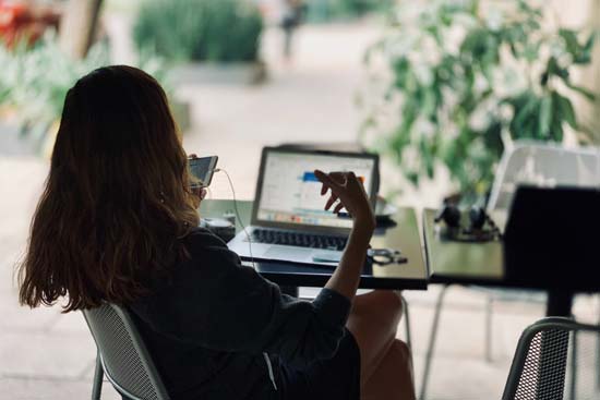 Eine Frau arbeitet mit ihrem Laptop und Handy Eine Frau arbeitet mit ihrem Laptop und Handy