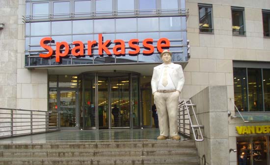 Der Eingang einer Bankagentur mit einer Statue eines Mannes davor Der Eingang einer Bankagentur mit einer Statue eines Mannes davor