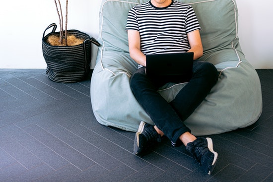 Solopreneur Intextbild Person sitz auf Sitzsack und tippt auf Laptop