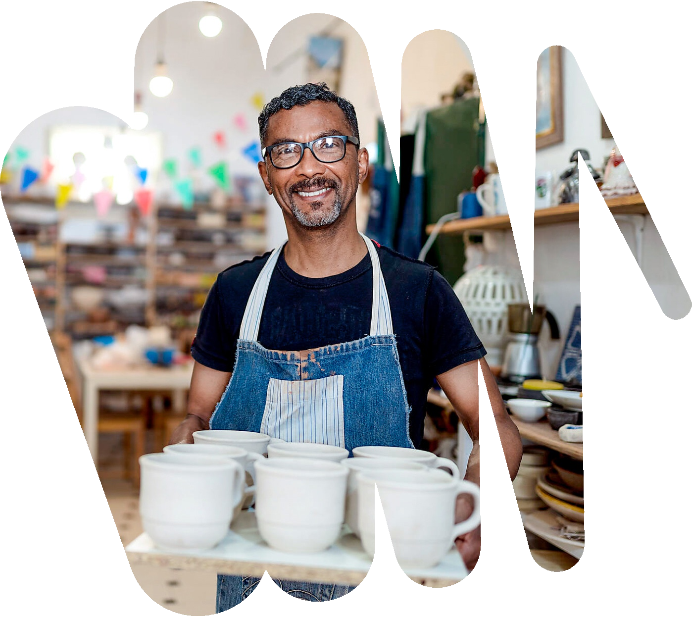 Ein Mann lächelt in die Kamera. Er hält ein Tablett mit mehreren Tassen.