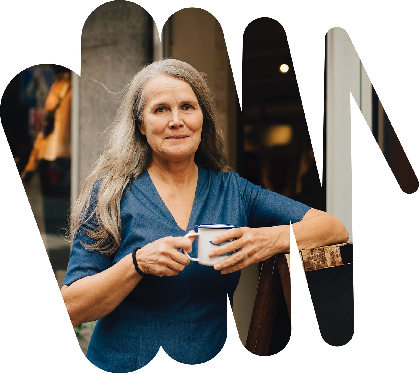 Eine Frau mit einer Tasse in der Hand lächelt in die Kamera