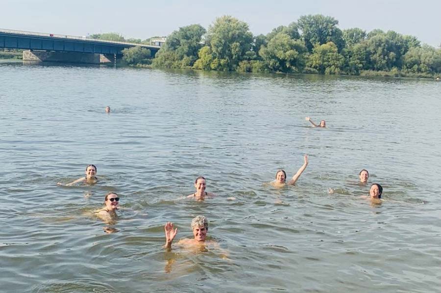 mehrere Personen schwimmen in einem See und winken