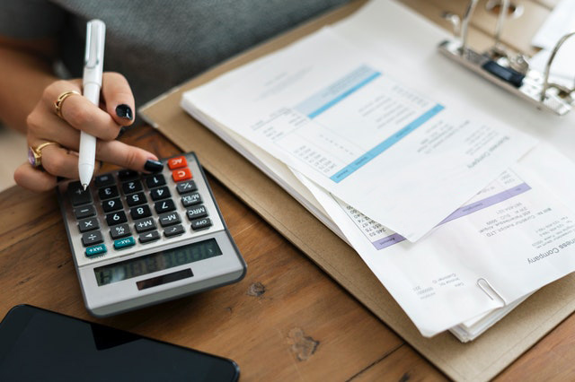Desk with a calculator on top and a woman checking her invoices