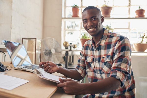 financial planning with ease men smiling at camera while sitting on his desk