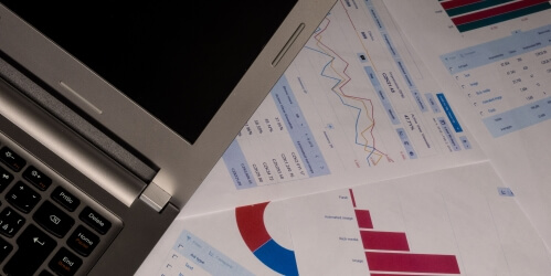metrics laptop with some metrics lying next to