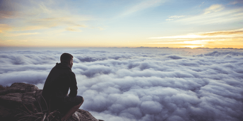 person sitting over clouds on mountain